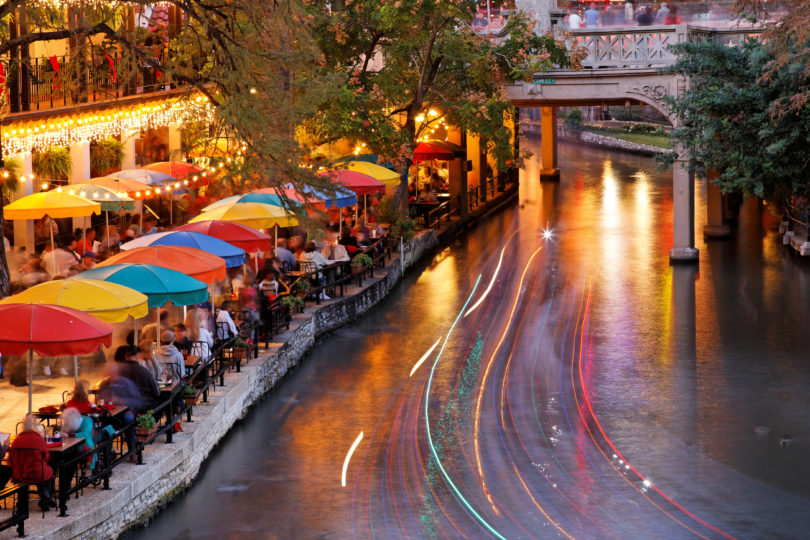 The passing of cruise boats captured as light trails along the popular River Walk area of San Antonio, Texas